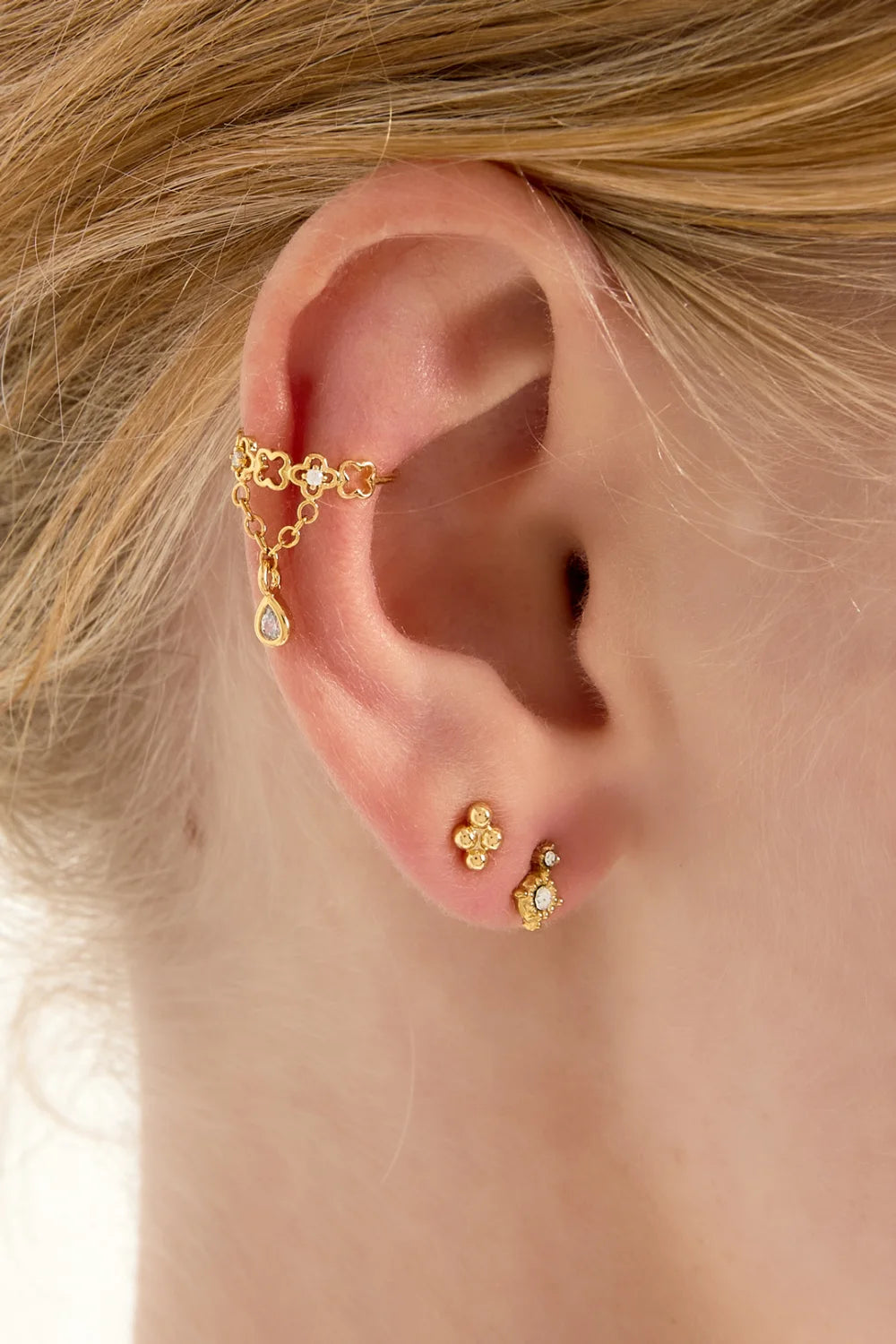 Fleur de Chance -ear cuff valkoisella taustalla, säädettävä korvakoru ilman korvareikää ja riippuvalla pisarakoristeella.