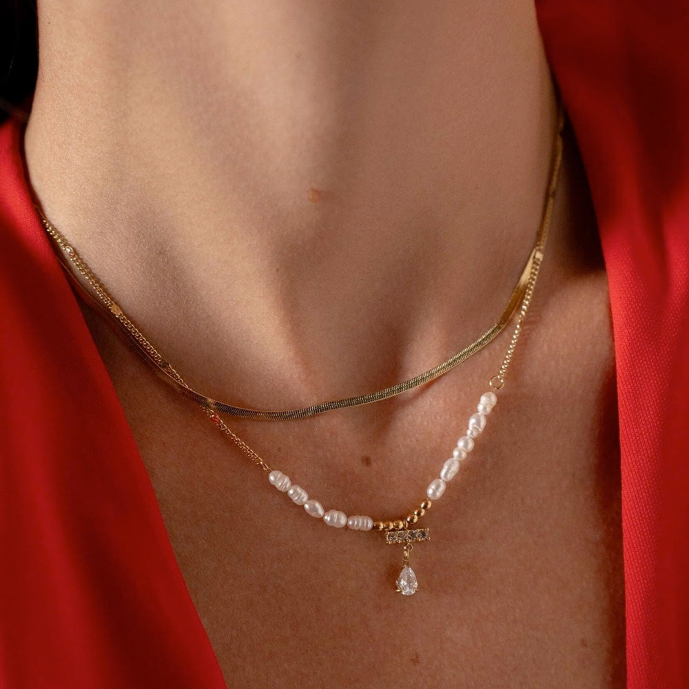 Kullanvärinen kerroksellinen helmikaulakoru pisarariipuksella mallin kaulassa.