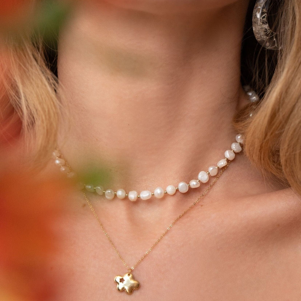 Helmi kaulakoru kaulassa kerrostettuna muiden korujen kanssa