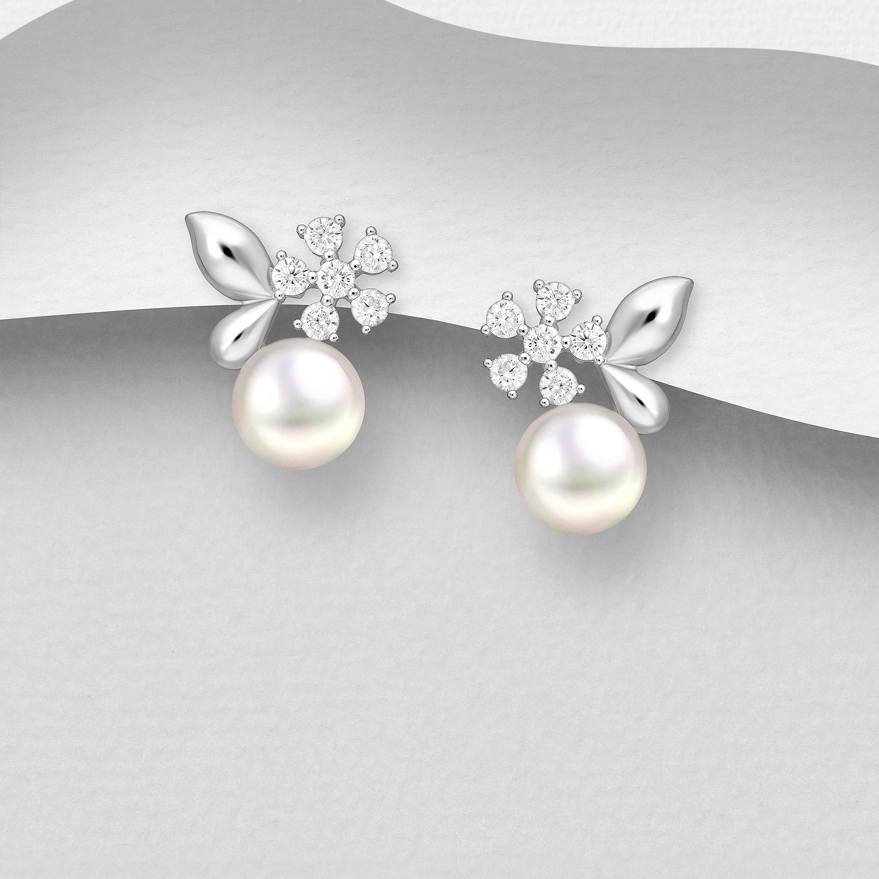 Hopeiset Helmi Linnea -korvakorut makeanvedenhelmellä ja kukkayksityiskohdilla.