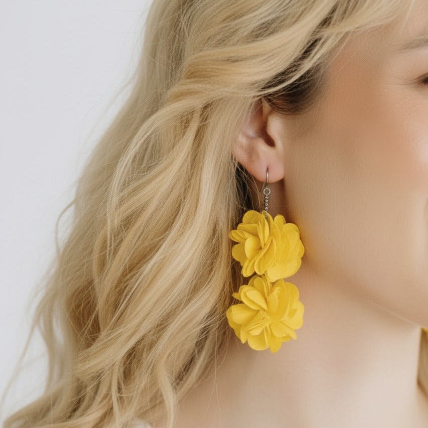 Keltaiset Roselle-korvakorut korvassa – kevyt ja näyttävä kukkamuoto.