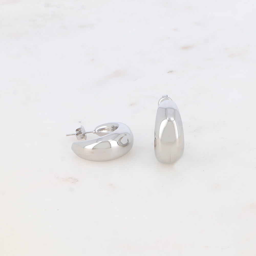 Modernit hopeiset rengaskorvakorut pyöristetyllä muodolla.