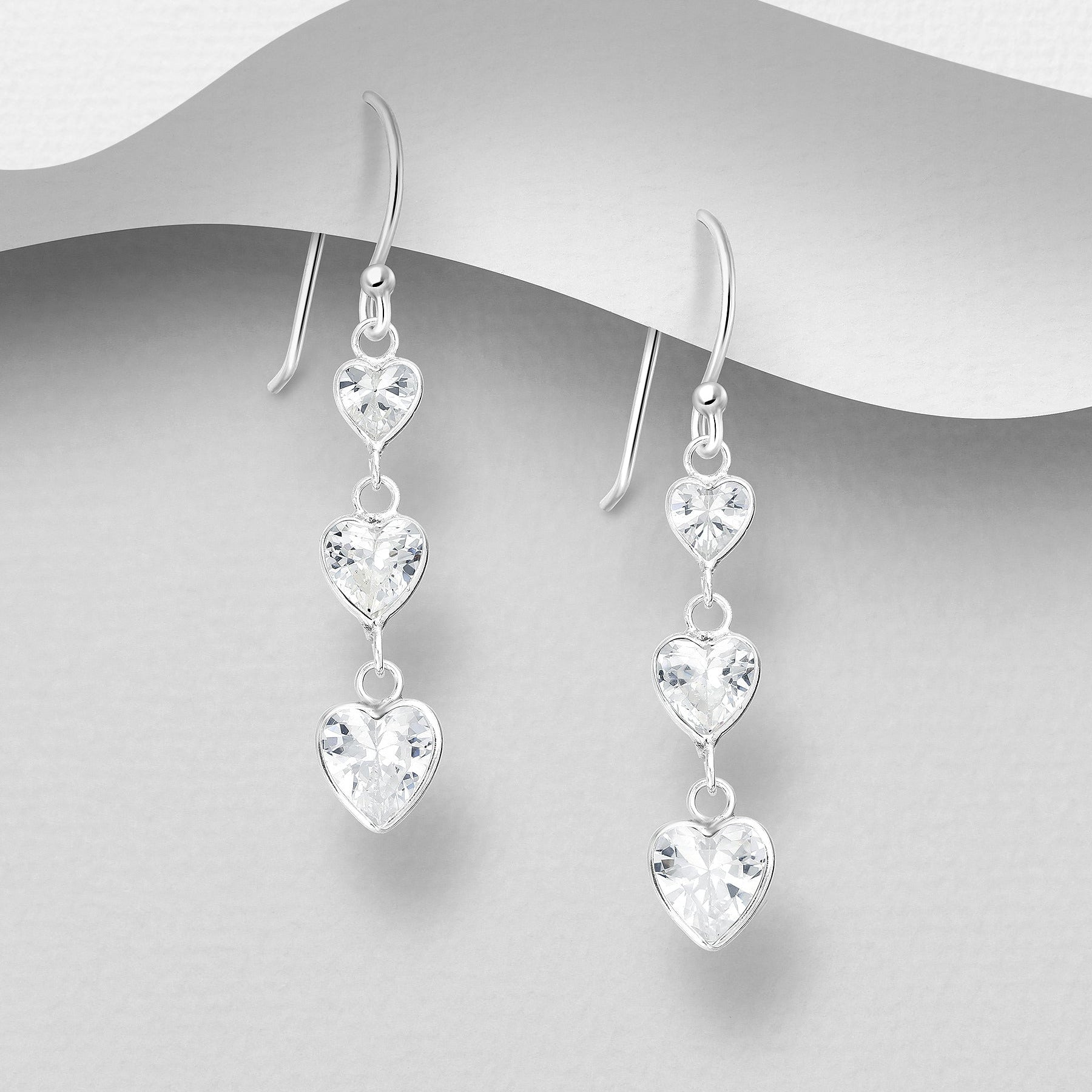 Sirot roikkuvat hopeakorvakorut kirkkailla CZ-sydämillä, kevyet ja kimaltavat.