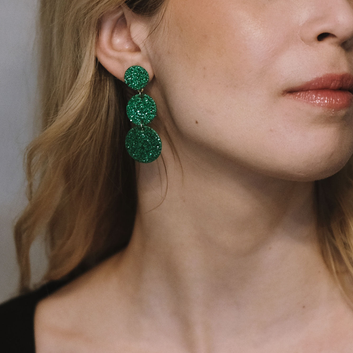 LEMPI®-korvakorut käytössä – Ilona-malli vihreänä versiona korvassa viistosta kuvattuna.