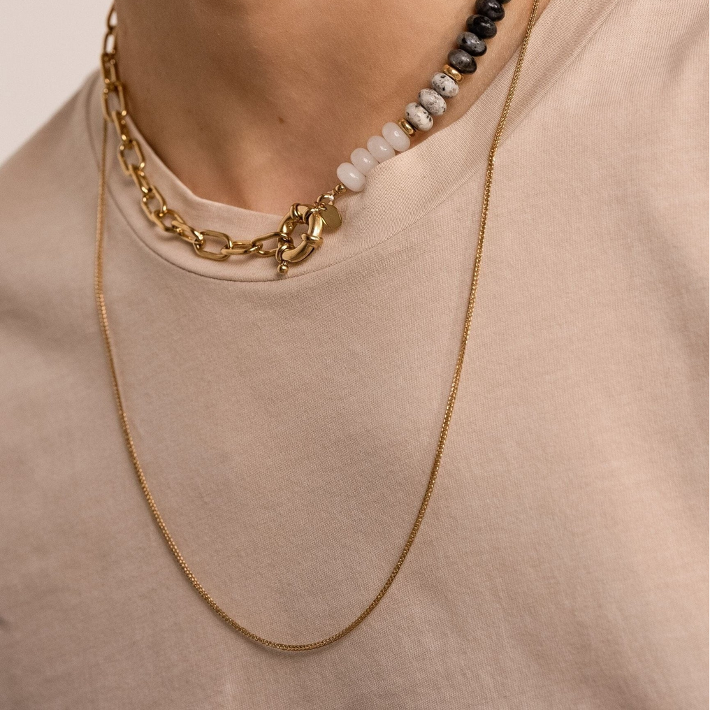 Pitkä kullanvärinen riipusketju minimalistisella ketjulla mallin kaulassa.