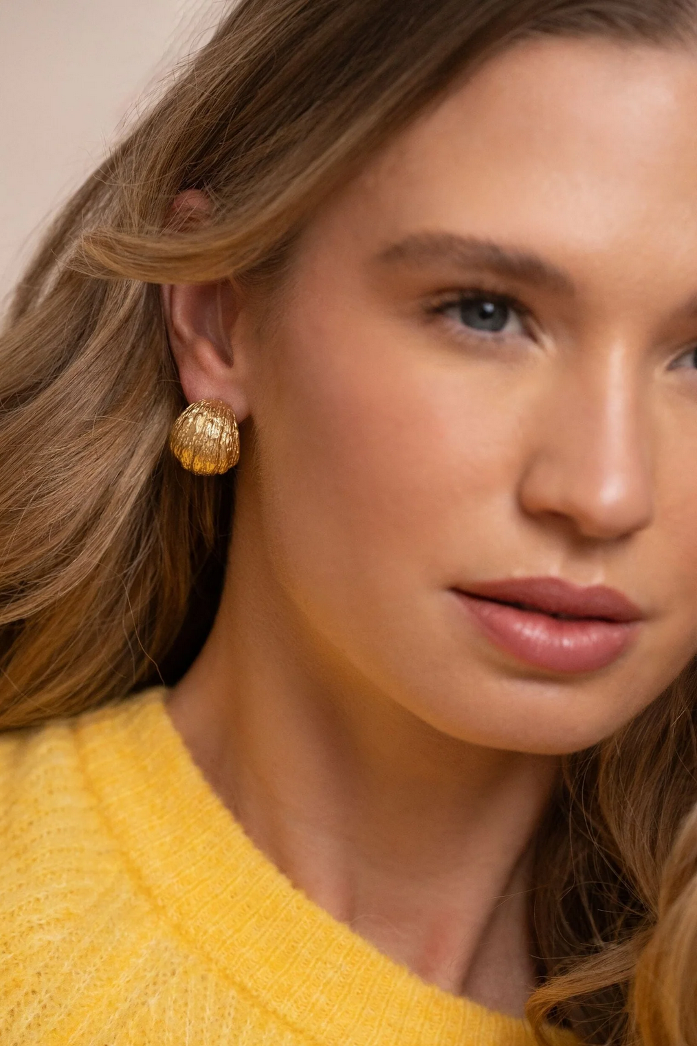 Modernit kultaiset rengaskorvakorut täyteläisellä muodolla korvassa kuvattuna.