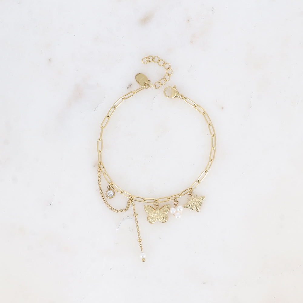 Kullanvärinen perhosrannekoru helmillä vaalealla pohjalla.