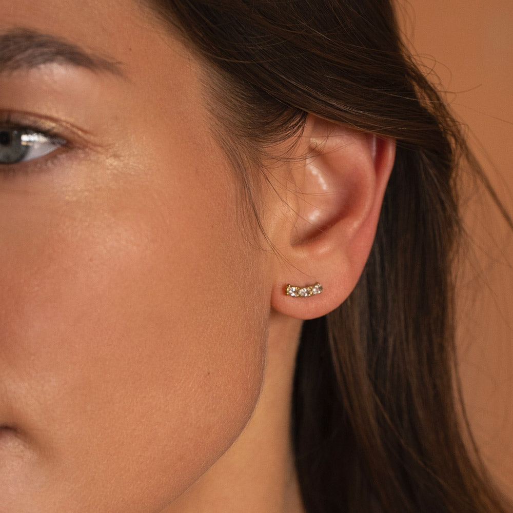 Kullanväriset pienet zirkoniakorvakorut kolmella kirkkaalla kivellä korvassa