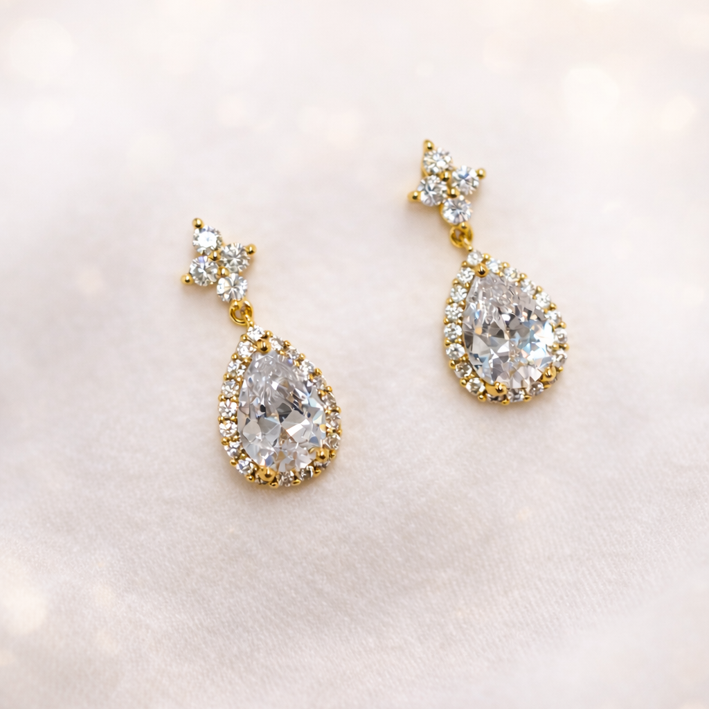 Kullansävyiset pisarakorvakorut cubic zirconia -kivillä valkoisella taustalla