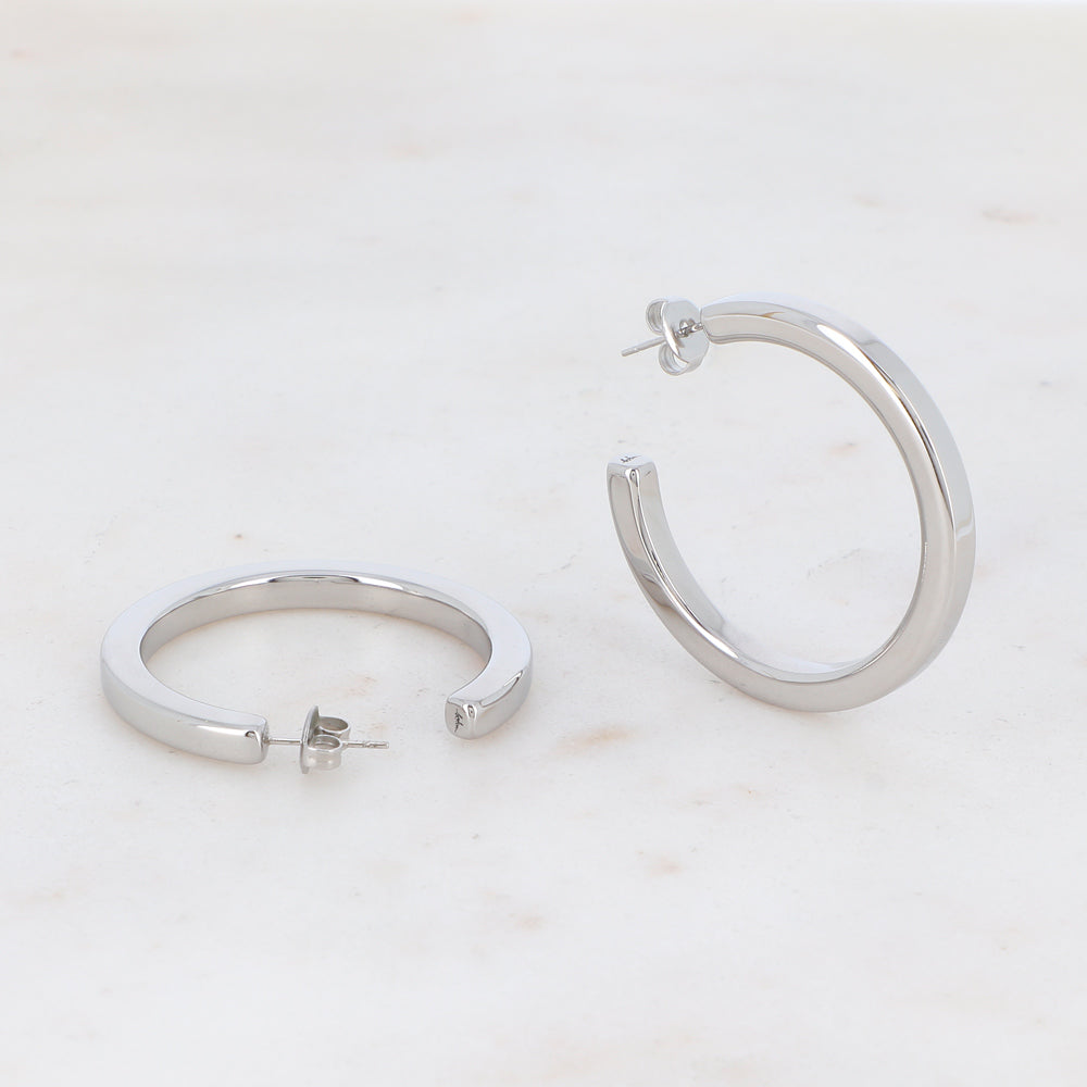 Klassiset hopeiset rengaskorvakorut sileällä pinnalla