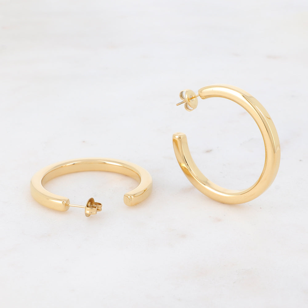 Klassiset kultaiset rengaskorvakorut sileällä pinnalla