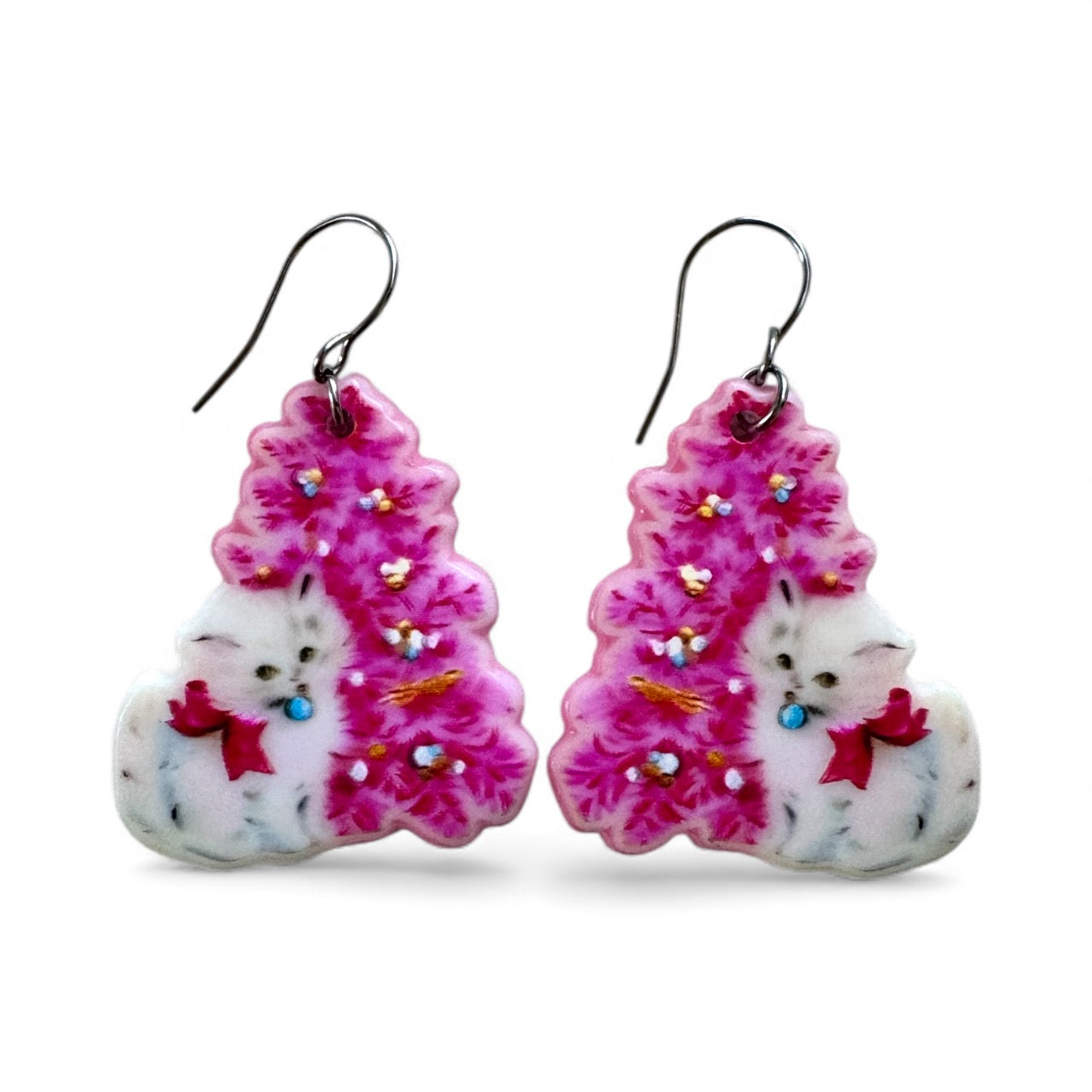 Joulukorvakorut, pinkin joulukuusen edessä valkoinen kissa, akryylia ja kirurginterästä.