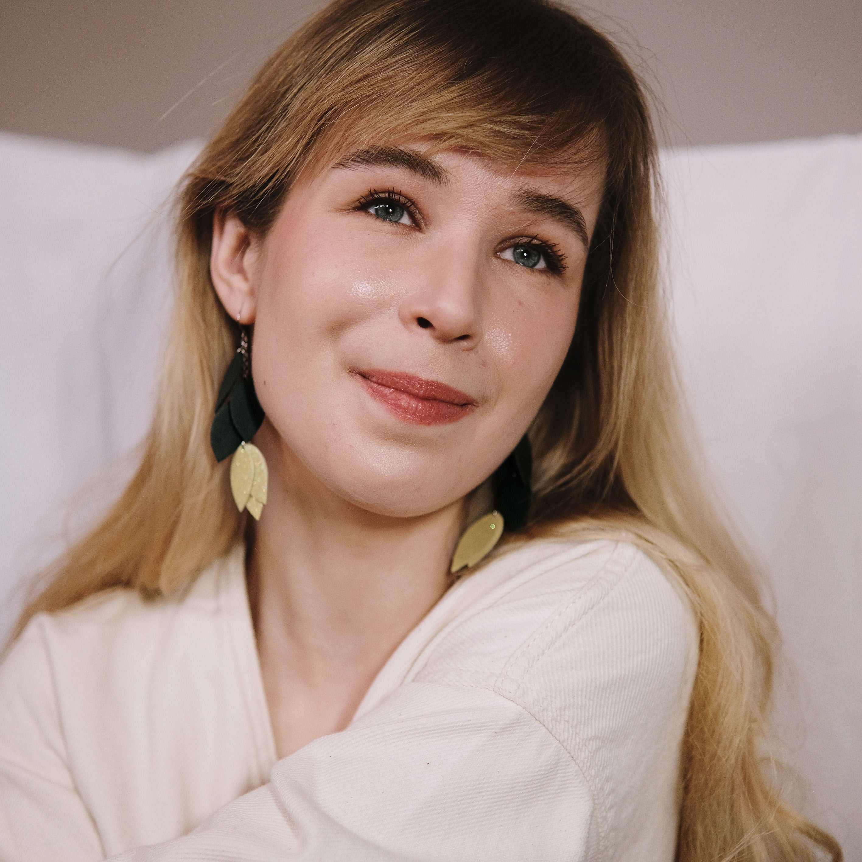 Kotimaiset LEMPI-korvakorut, joissa on lehtimäinen keinonahkainen koristeosa ja sitruunankeltainen glitteryksityiskohta mallin korvassa.