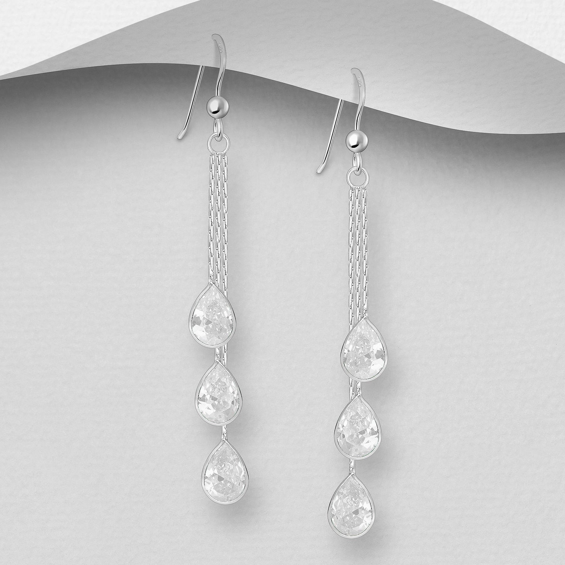 Pitkät roikkuvat hopeakorvakorut kolmella kirkkaalla kristallilla, siro ja kimaltava malli.