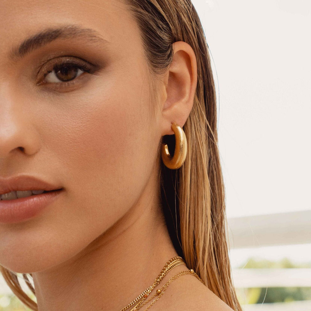 Näyttävät kullanväriset ovaalit rengaskorvakorut korvassa