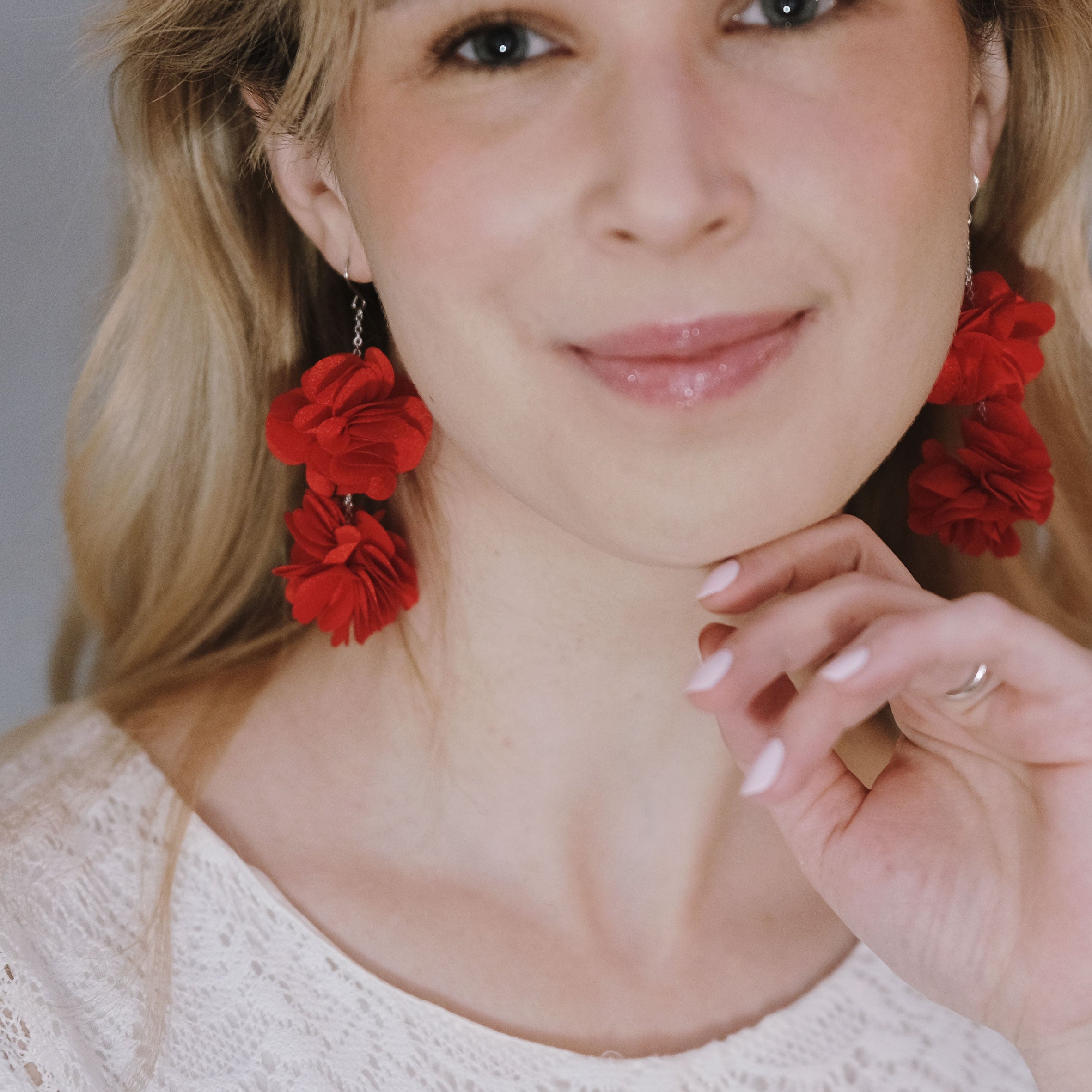 Punaiset käsintehdyt Roselle-korvakorut, joissa kaksi kerrostettua kangaskukkaa kevyessä kirurginteräsketjussa.