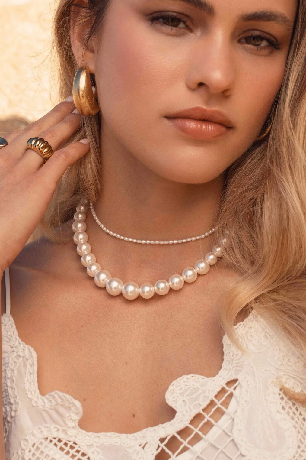 Minimalistinen choker-helmikaulakoru kullan sävyllä kaulassa kuvattuna.