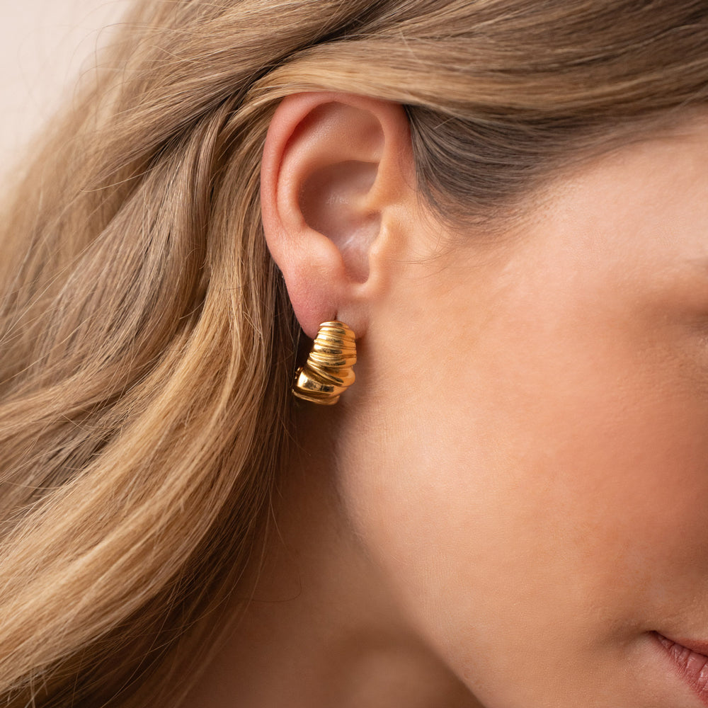 Kullanväriset teksturoidut rengaskorvakorut korvassa lähikuvassa