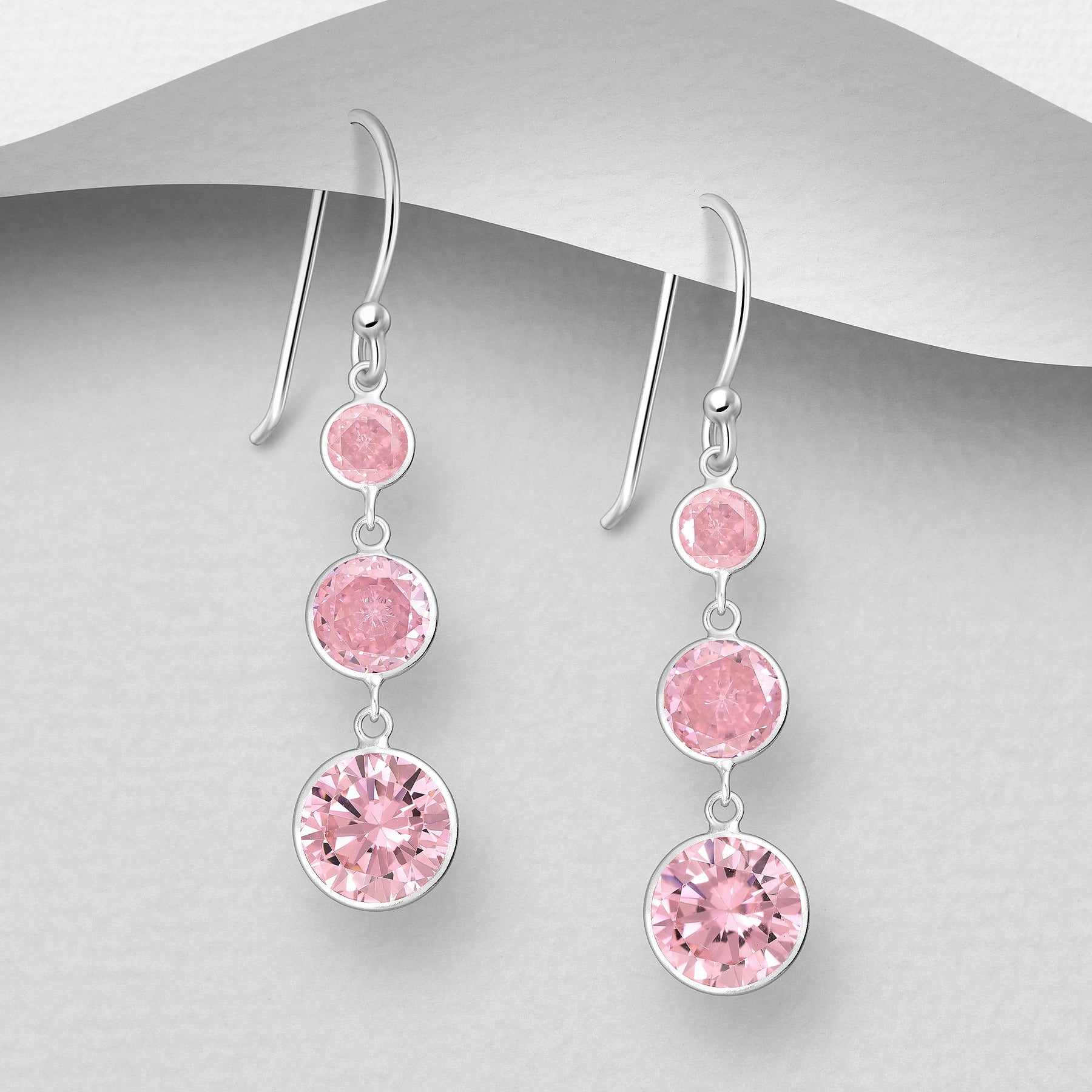 Pitkät roikkuvat hopeakorvakorut kolmella vaaleanpunaisella kristallilla.