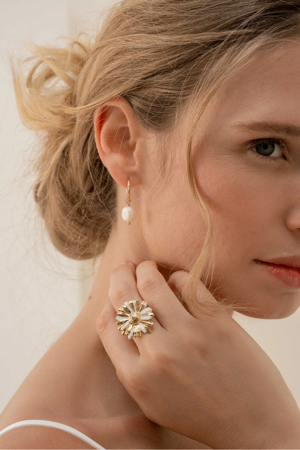 Kullanväriset rengaskorvakorut makeanvedenhelmellä mallin korvassa kuvattuna.