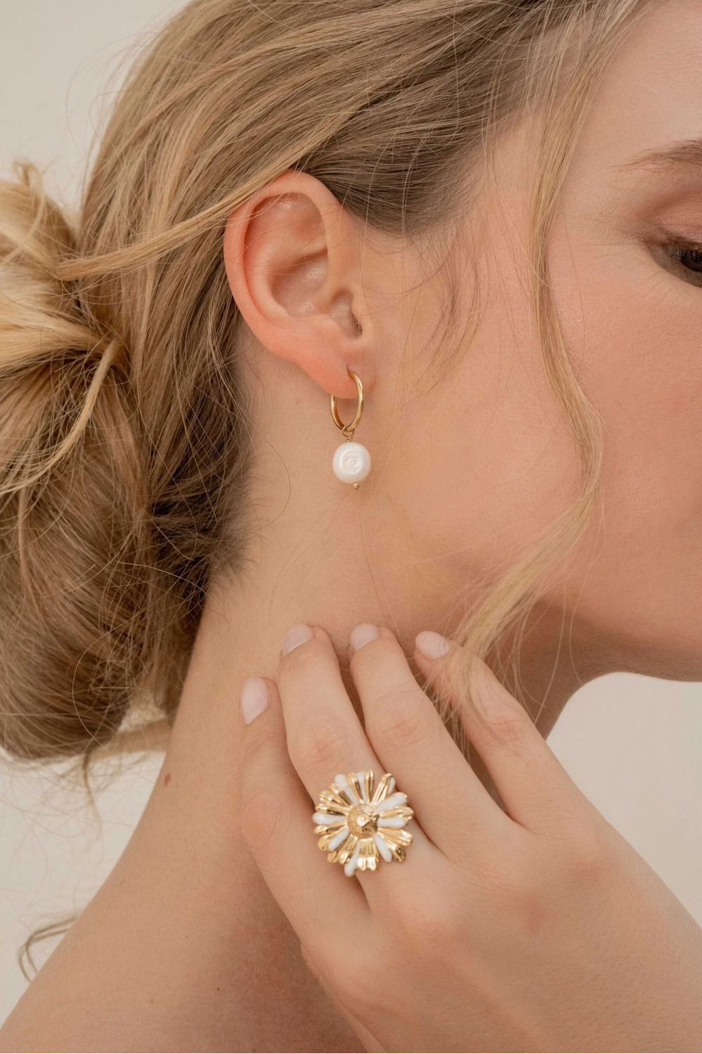 Kullanväriset helmikorvakorut makeanvedenhelmellä mallin korvassa.